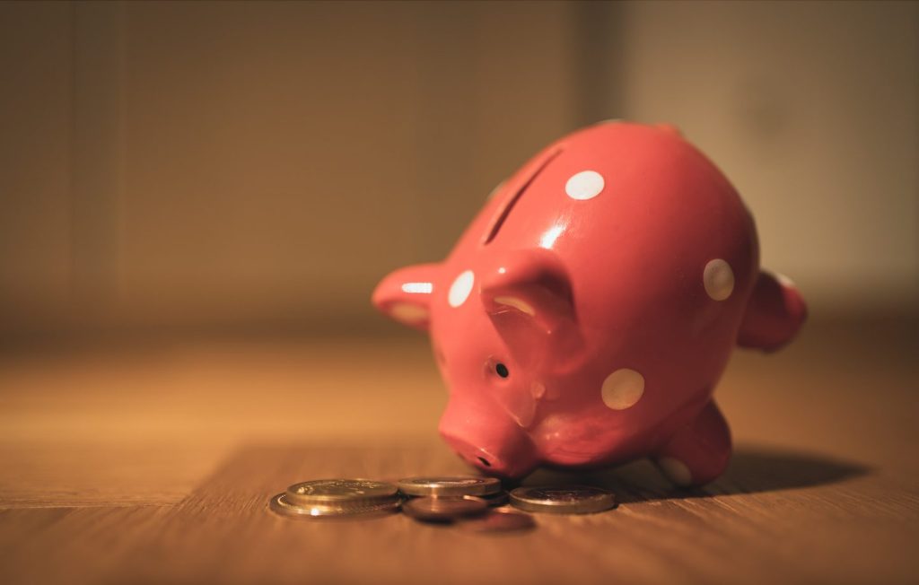 pink piggy bank leaning over and eating gold coins 